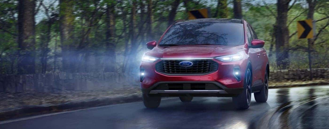 Red 2023 Ford Escape driving with the headlights on
