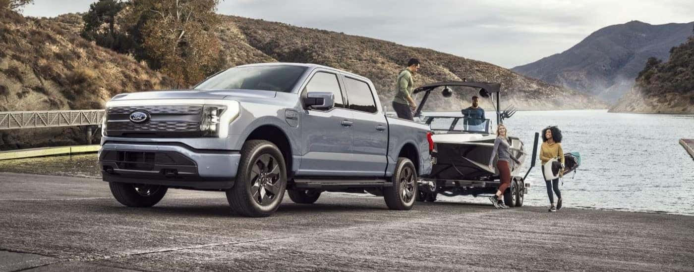 A silver 2024 Ford F-150 Lightning is shown towing a boat