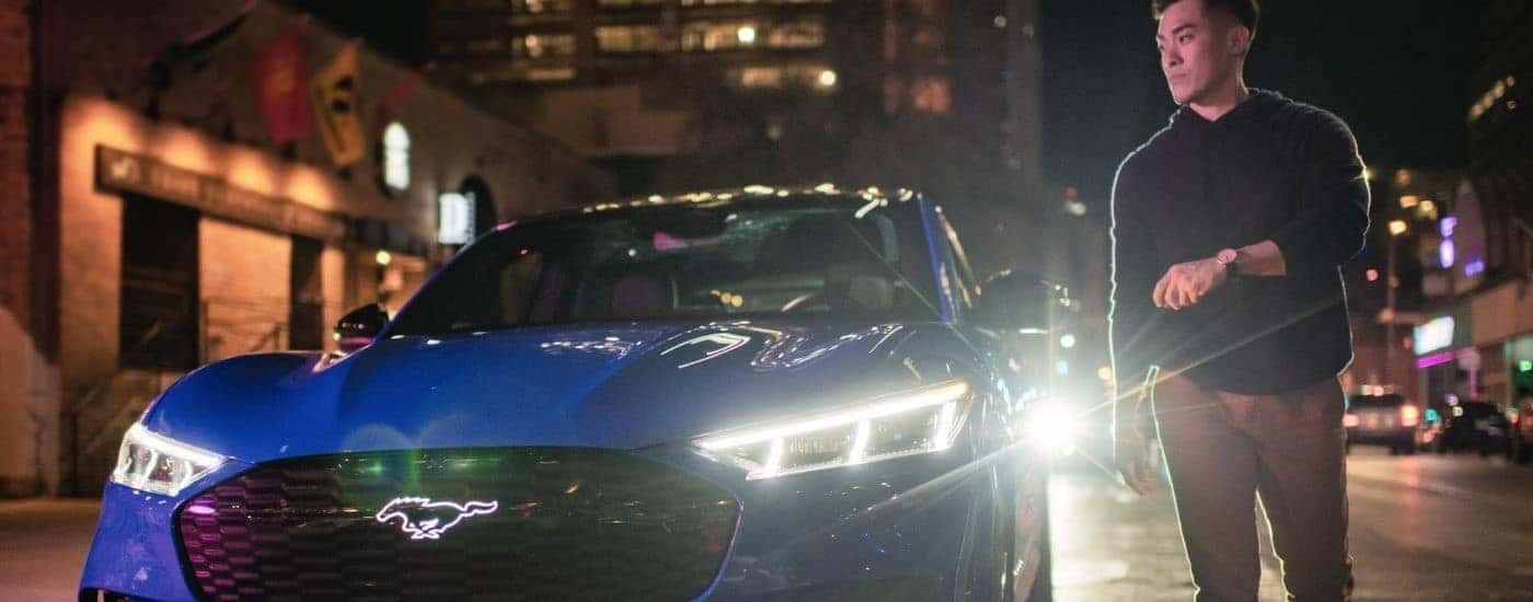A person walking by a parked blue 2023 Ford Mustang Mach-E GT