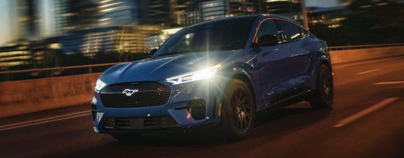 Blue 2024 Ford Mustang Mach-E driving through a city at night