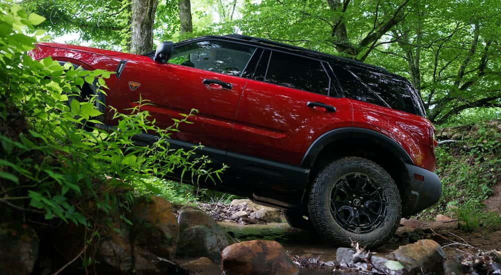 Side of a red 2026 Ford Bronco Sport driving up a hill.