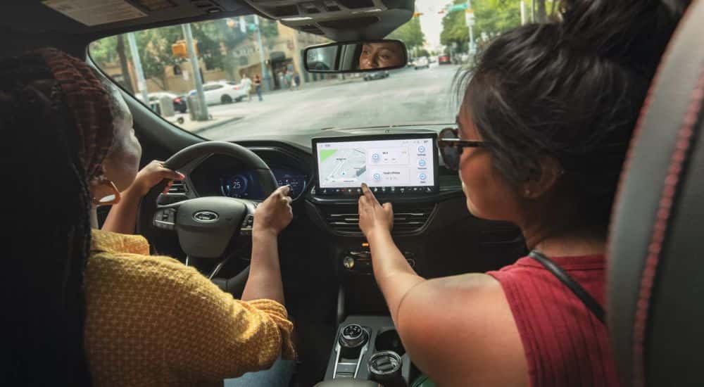 Passenger adding to the GPS in a 2026 Ford Escape while a driver operates the vehicle