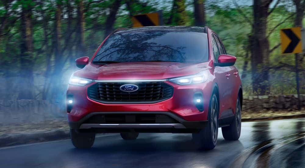 Red 2026 Ford Escape driving along a wooded road