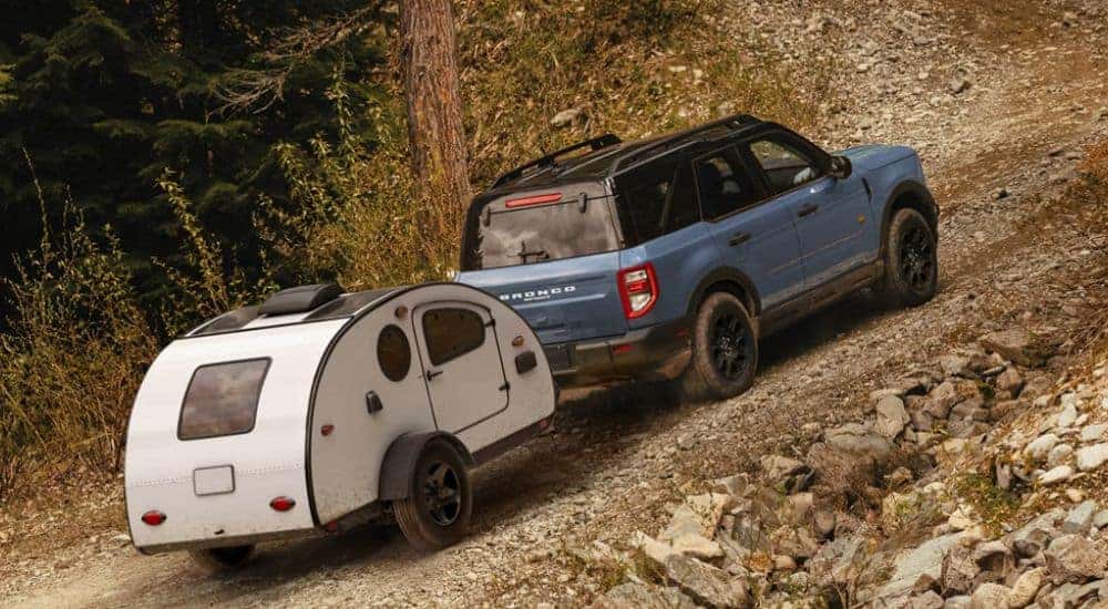 Blue 2026 Ford Bronco Sport towing a camper up a hill