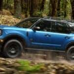 Blue 2026 Ford Bronco Sport driving through the woods