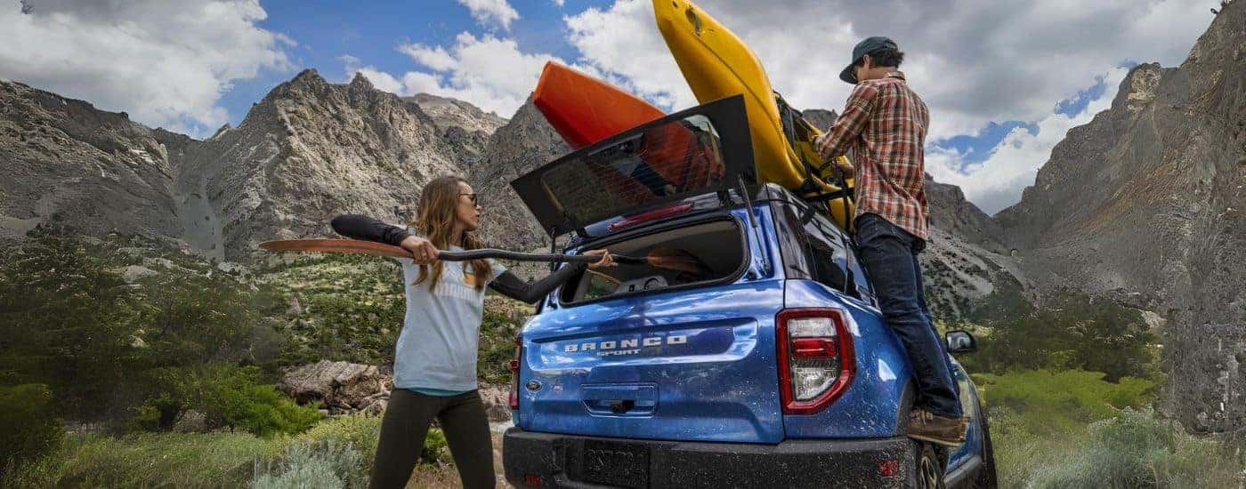 Two people loading kayaks into a blue 2022 Ford Bronco Sport.