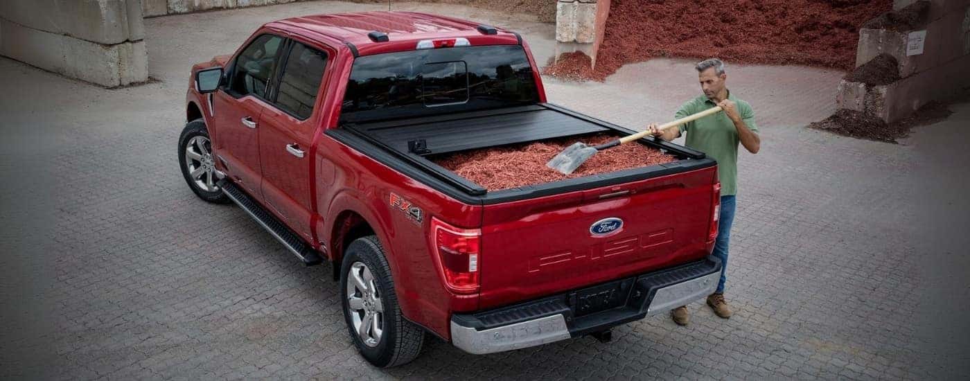 A red 2023 Ford F-150 with mulch in truck bed.