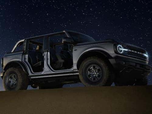 2024 Ford Bronco parked on a sand hill under the stars with the doors and roof off
