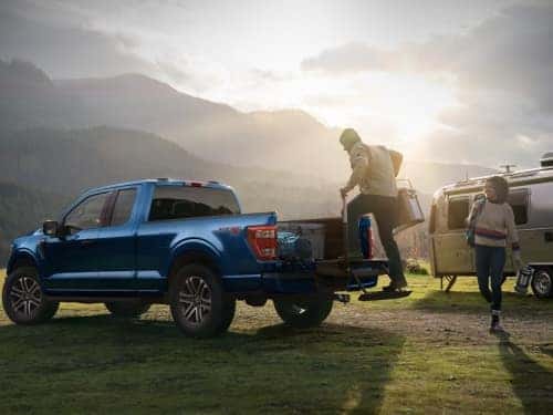 2024 Ford F-150 view of man using tailgate step to put ice chest in back of truck