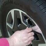 A person checking their tire pressure while using a psi measuring tool