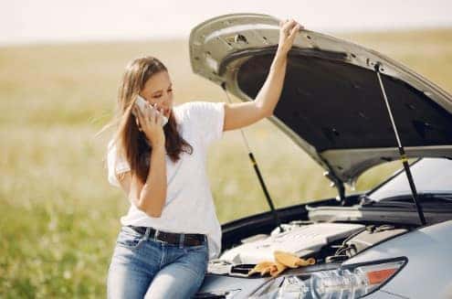 Woman upset her car broke down on her cell phone.