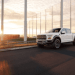 Used Ford truck driving down a highway surrounded by windmills.
