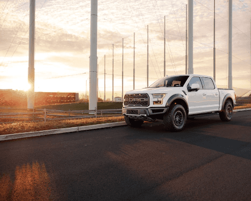 Used Ford truck driving down a highway surrounded by windmills.