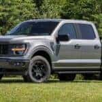 A grey 2024 Ford F-150 STX is shown from the front at an angle after leaving a dealer that has trucks for sale near Hayward.