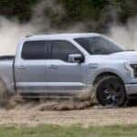 A silver 2024 Ford F-150 Lightning Lariat is shown from the side while off-road.