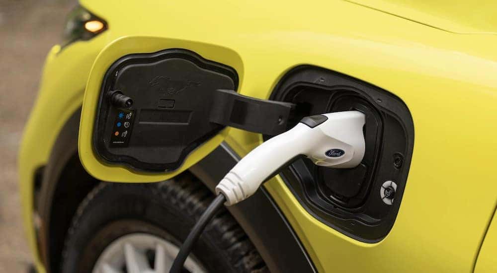 A yellow 2024 Ford Mustang Mach-E is shown charging.