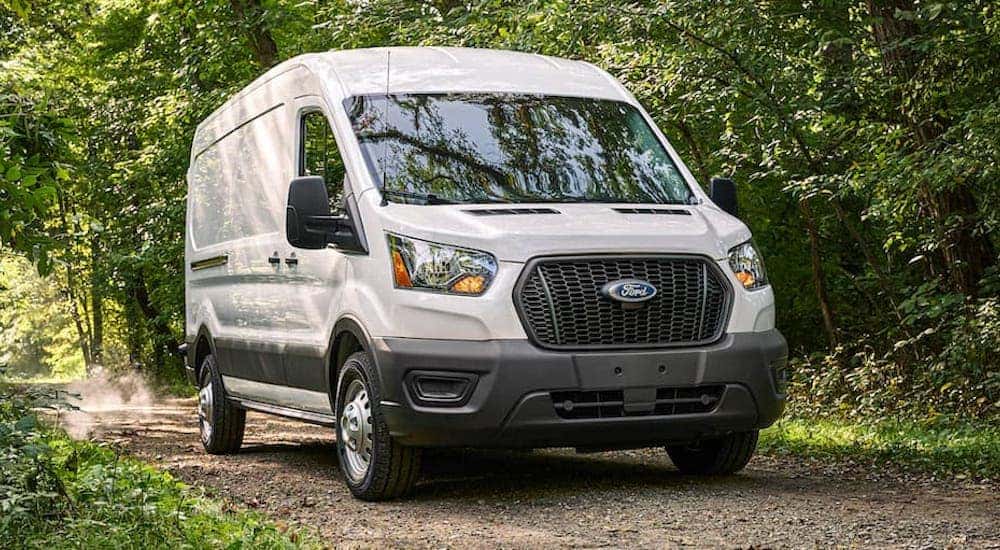A white 2021 Ford Transit Connection is shown driving in a forest.