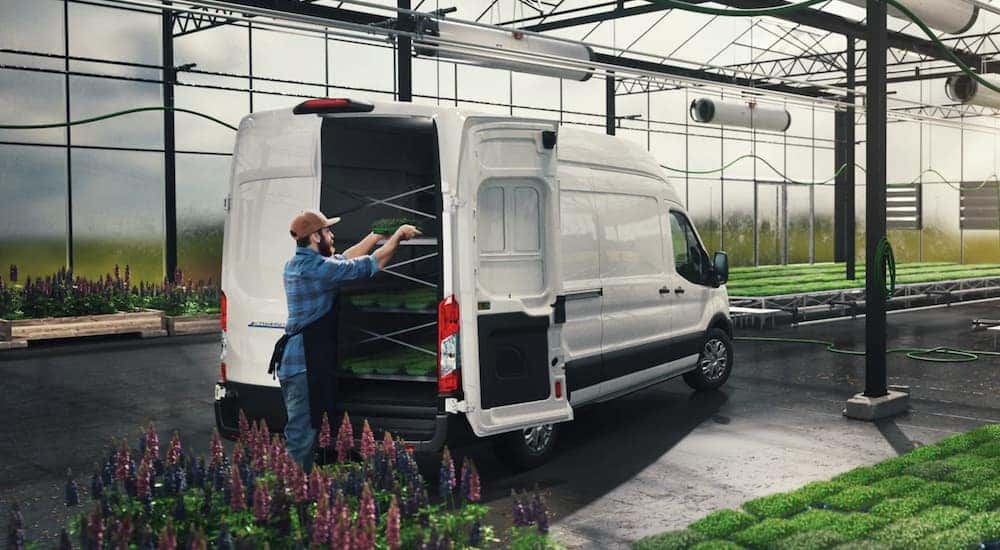 A person is shown loading gear into the back of a white 2022 Ford E-Transit.