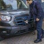 A grey 2023 Ford E-Transit is shown being charged.