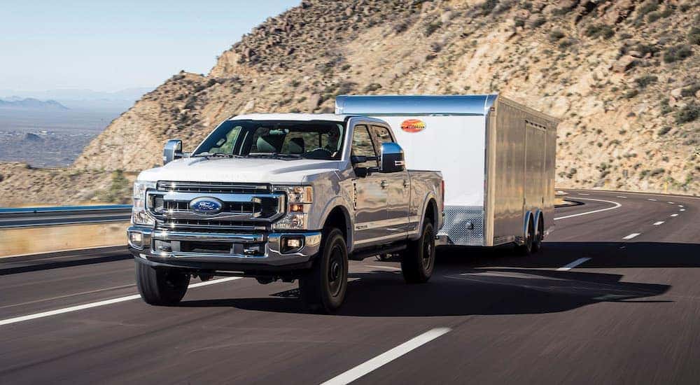 A white 2024 Ford F-350 Super Duty is shown towing a trailer from a dealer with commercial trucks for sale.