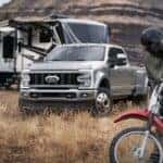 A grey 2024 Ford F-450 Super Duty is shown parked off-road in a camp.