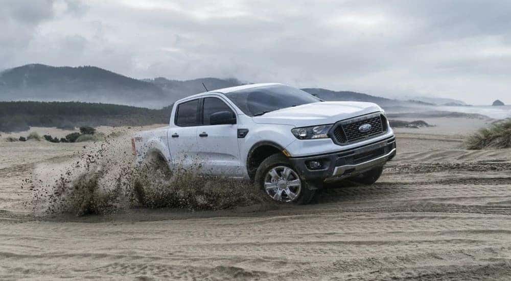 A white 2023 Ford Ranger FX4 kicking up sand while off-roading.