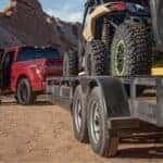 A red 2025 Ford F-150 towing a trailer after visiting a Ford dealer near Livermore.
