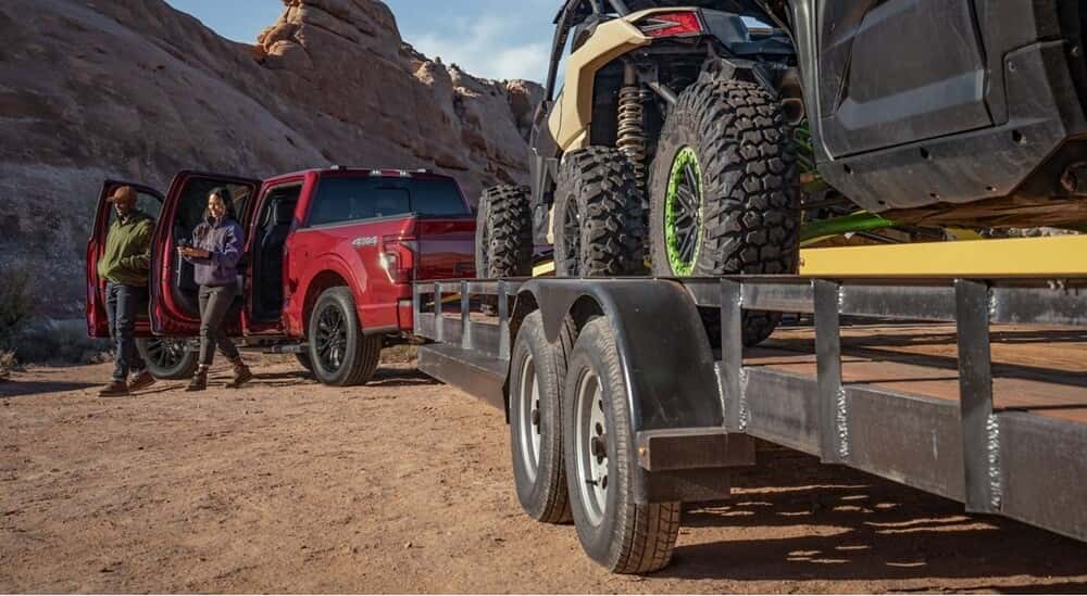 A red 2025 Ford F-150 towing a trailer after visiting a Ford dealer near Livermore.