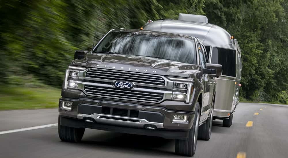 Front view of a black 2025 Ford F-150 Platinum Plus towing a trailer.