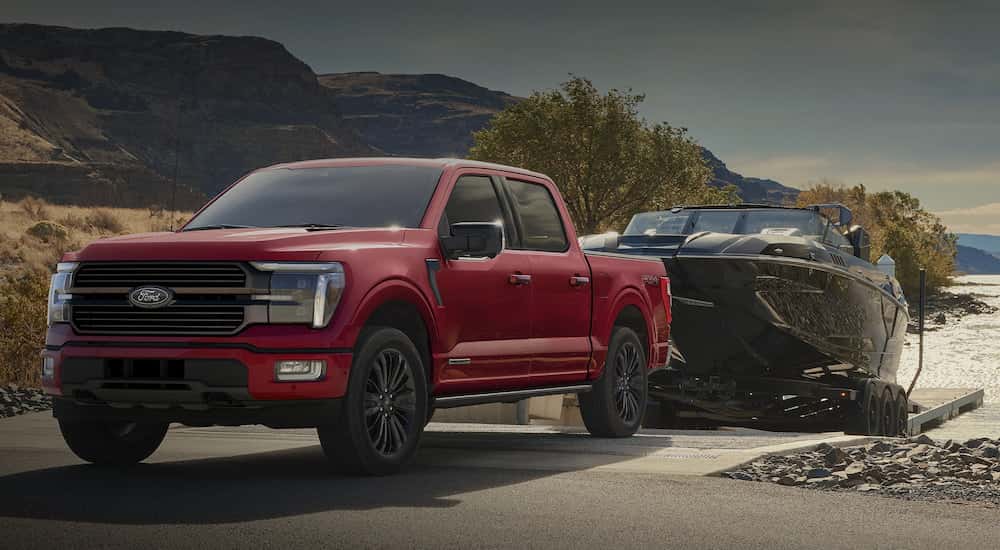 Red 2025 Ford F-150 STX towing a boat out of a lake after visiting a Ford dealer near Livermore.