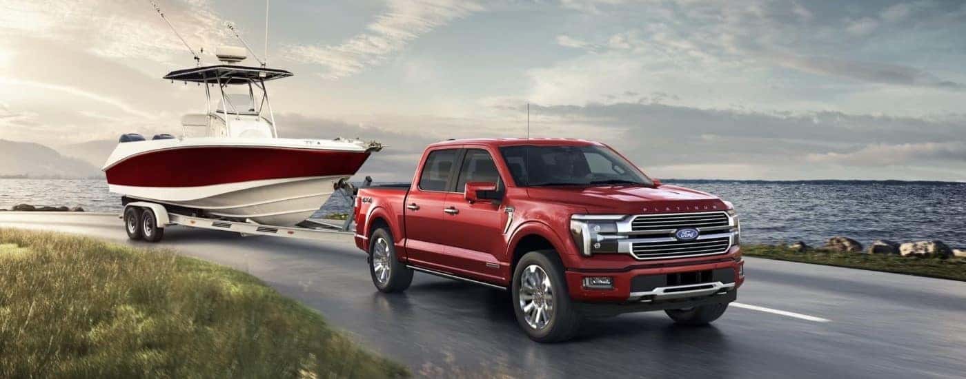 A red 2024 Ford F-150 towing a boat.