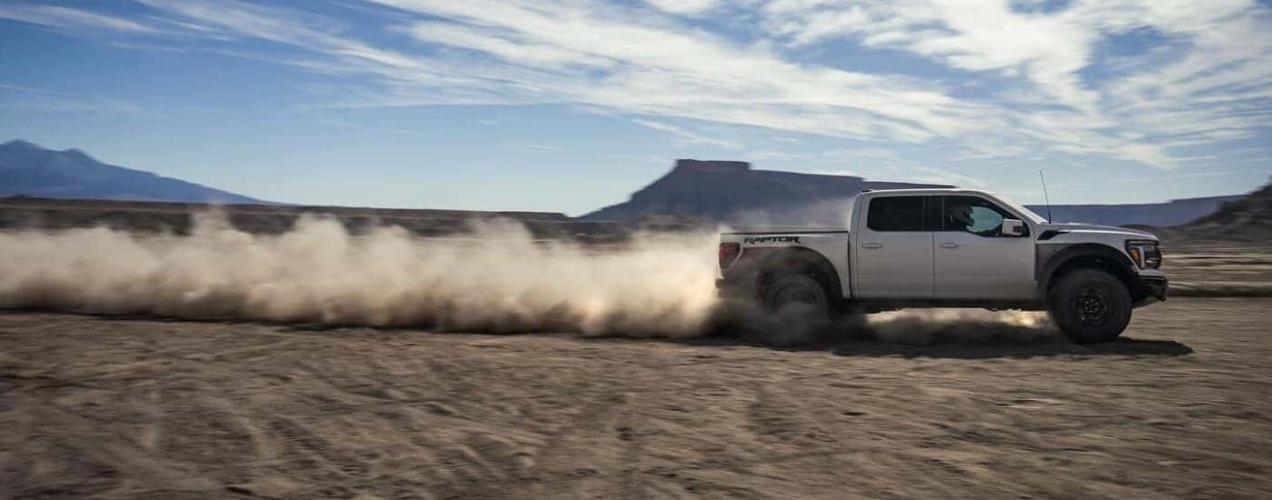 A white 2024 Ford F-150 Raptor R kicking up dust.