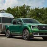 Green 2025 Ford Maverick towing an Airstream trailer down the road.