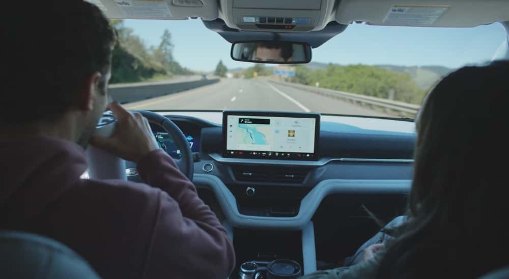 Two people drive a 2025 Ford Explorer down the street