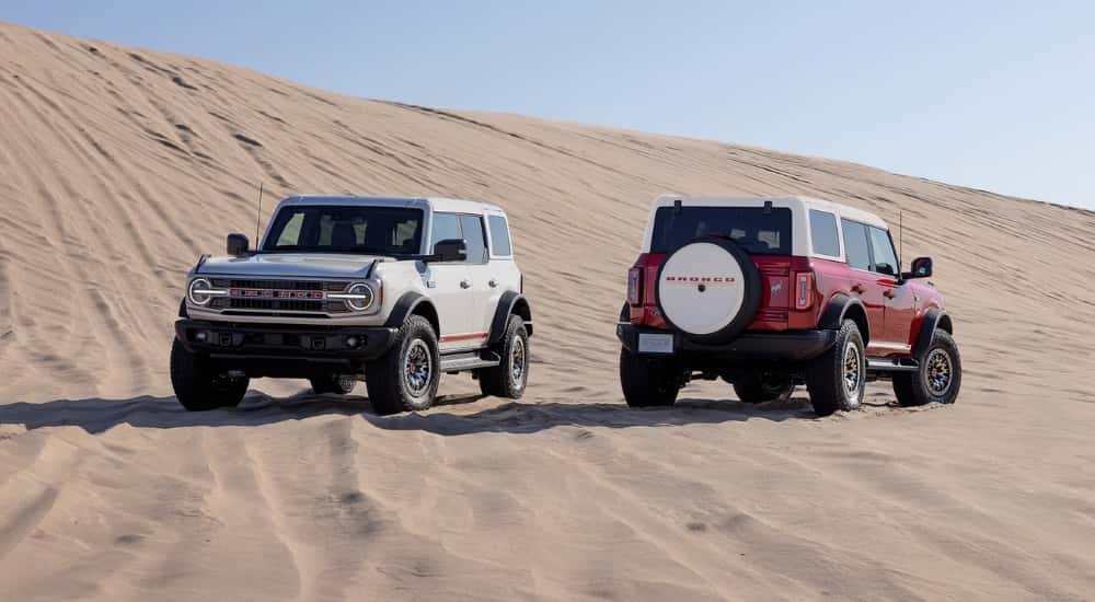 A white and a red 2026 Ford Bronco 60th Anniversary parked off-road