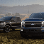 A blue and a black 2026 Ford F-150s parked off-road
