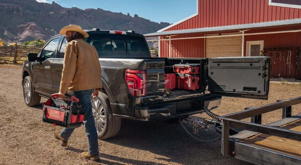 Black 2026 Ford F-150 towing a trailer and tools in the bed