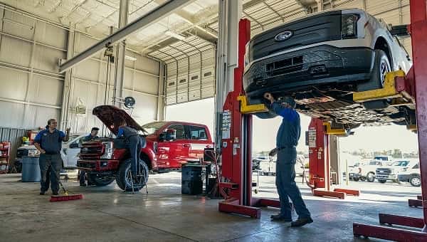 Ford service bay with Ford F-150 on a lift and mechanic working on it
