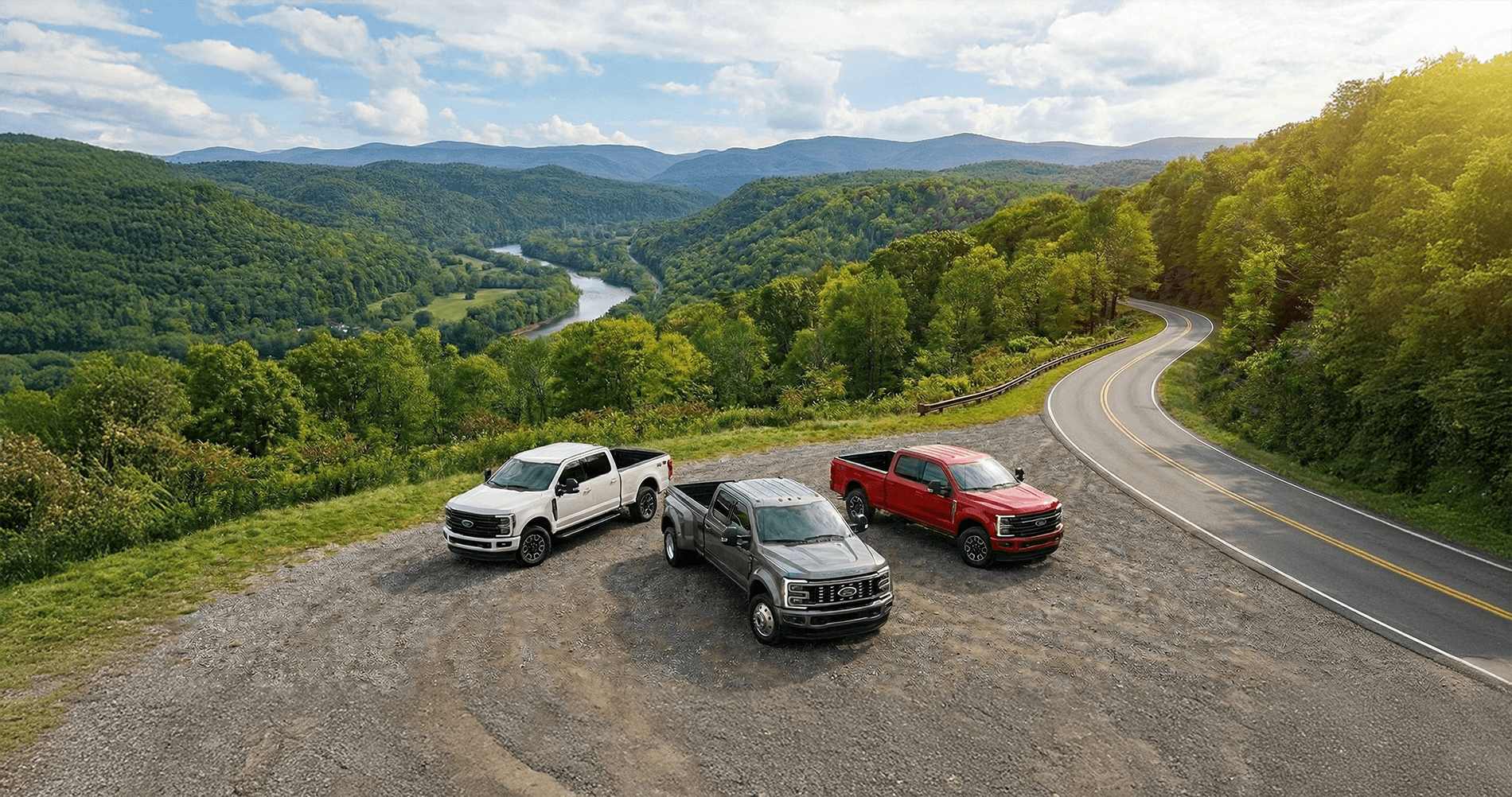 Three different 2026 Ford Super Duty trim levels parked on a gravel pull off in the mountains