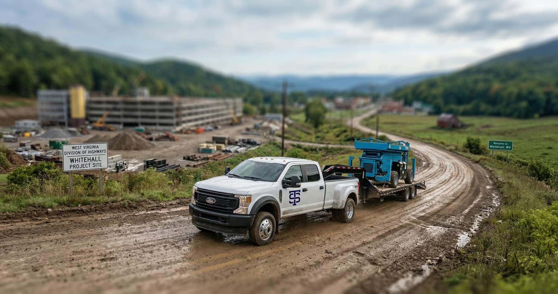 Ford Super Duty truck pulling a trailer with heavy equipment up a dirt road to a construction site in Whitehall, WV