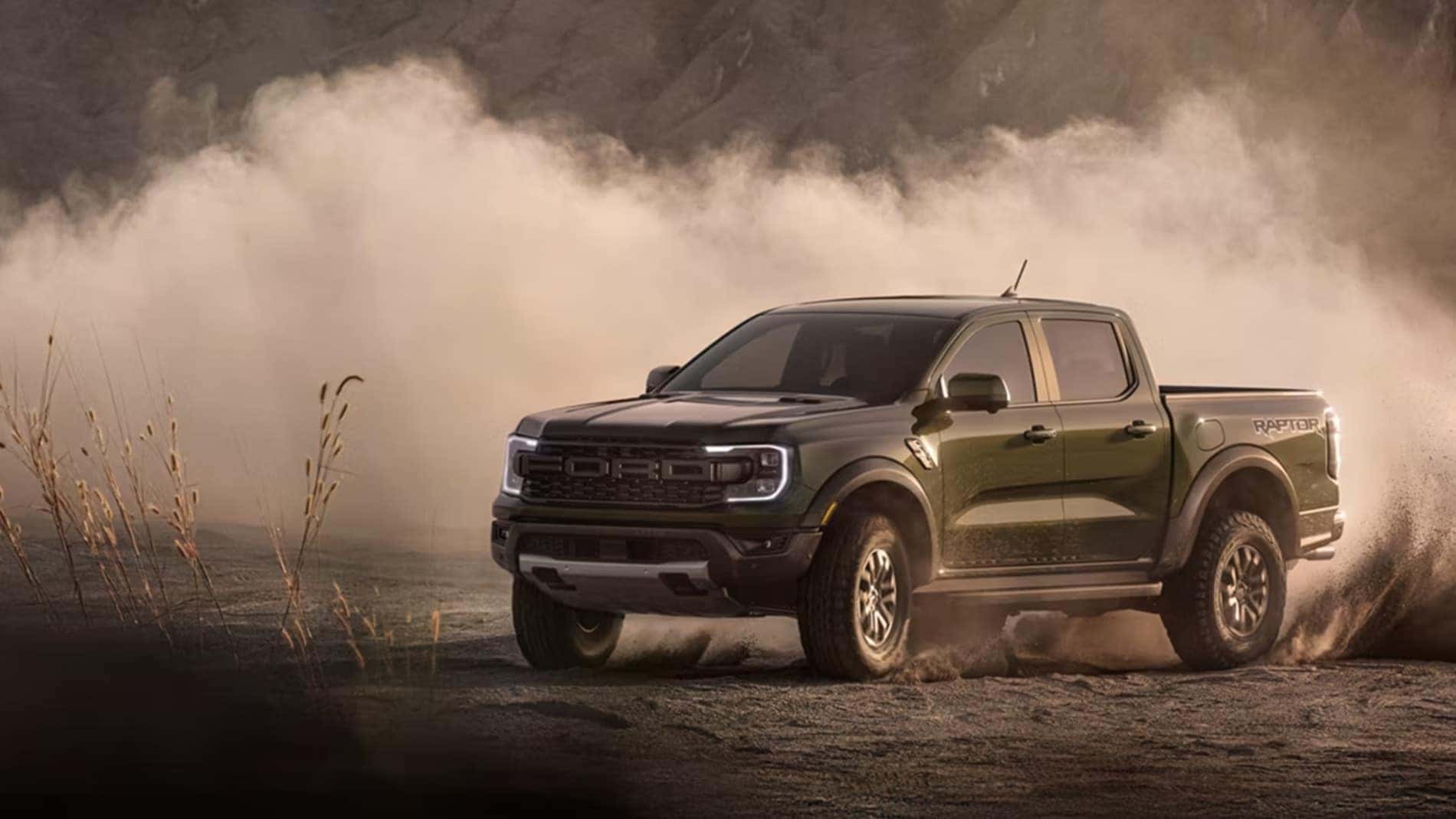 2026 Ford Ranger Raptor driving through dirt with dust cloud on rugged terrain