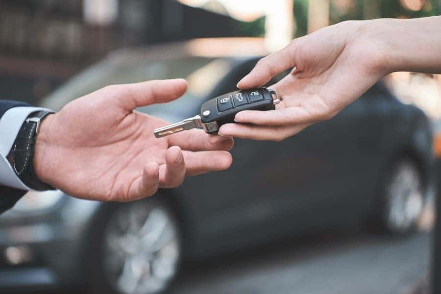 hand giving car key to another hand