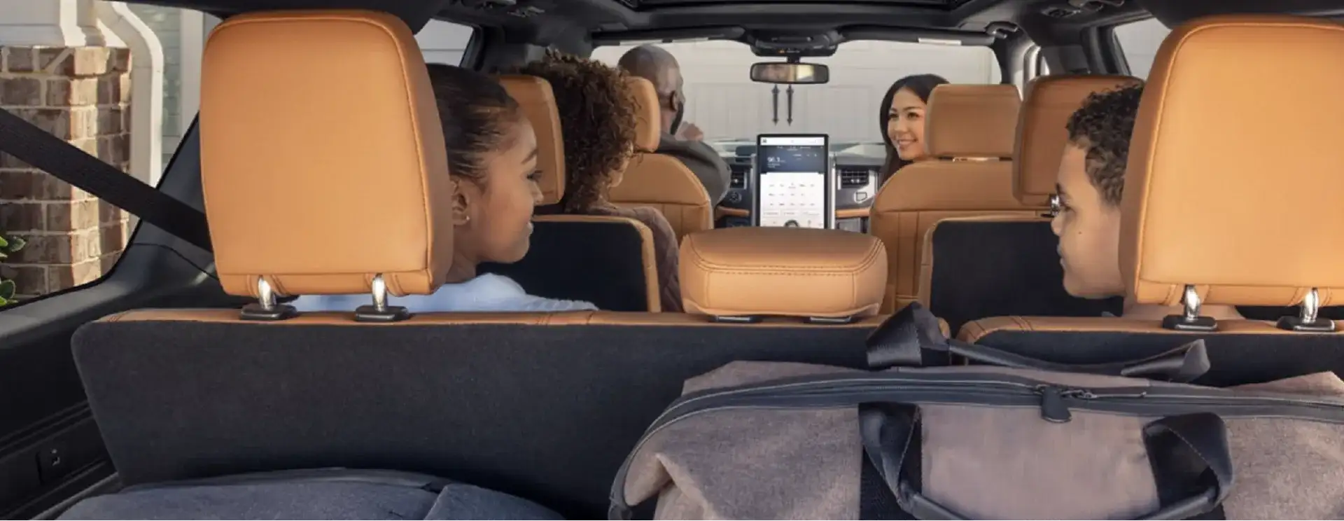 Family of five seated inside a Ford SUV with tan leather seats, viewed from the cargo area