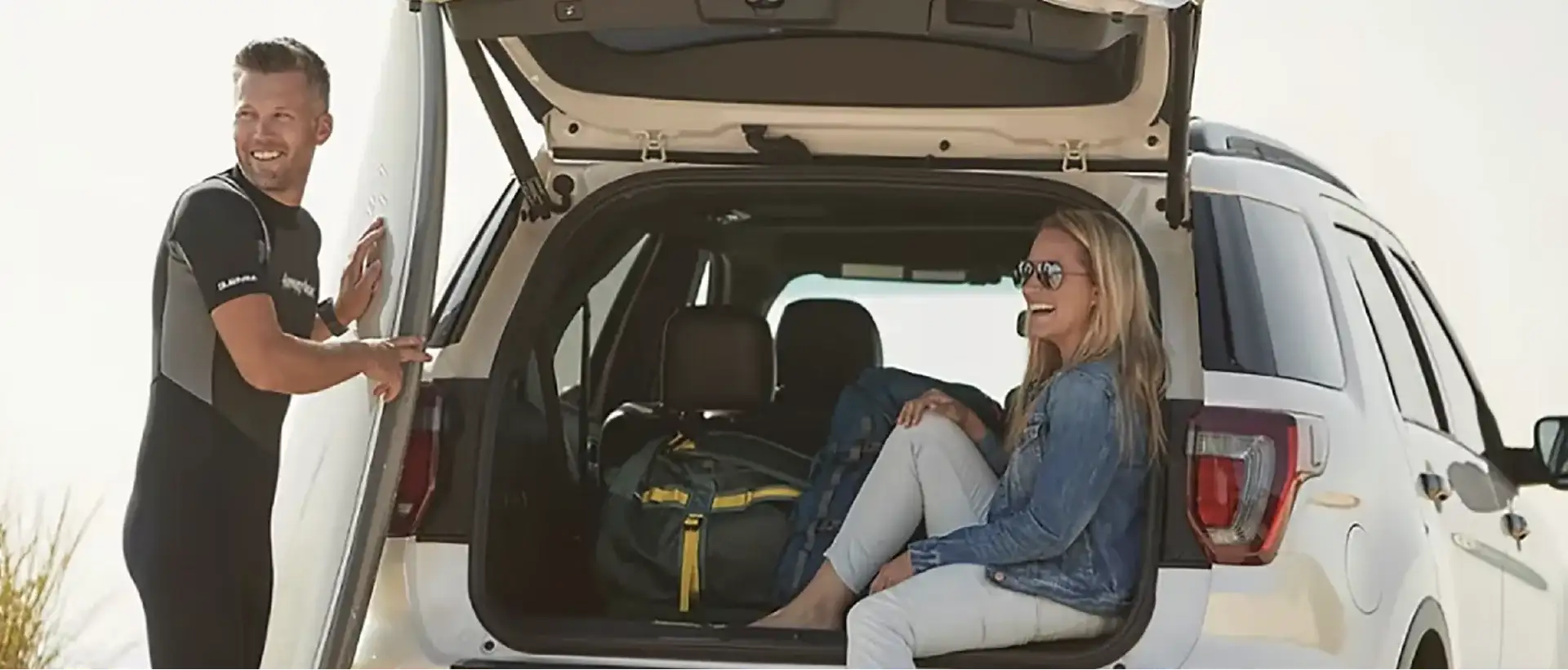 Couple loading gear into a certified pre-owned Ford SUV with the liftgate open
