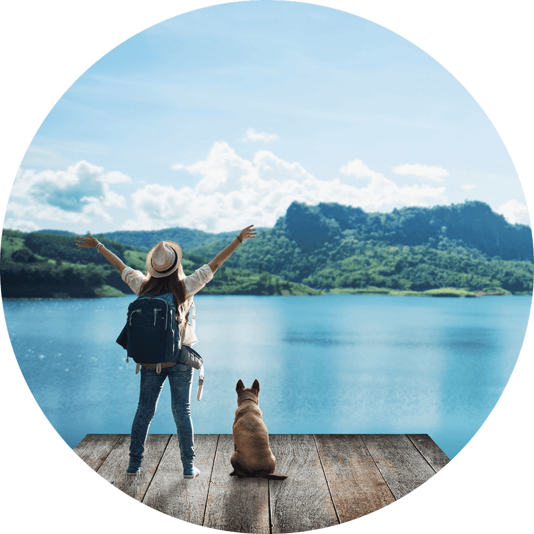 woman and dog standing in front of mountains and water