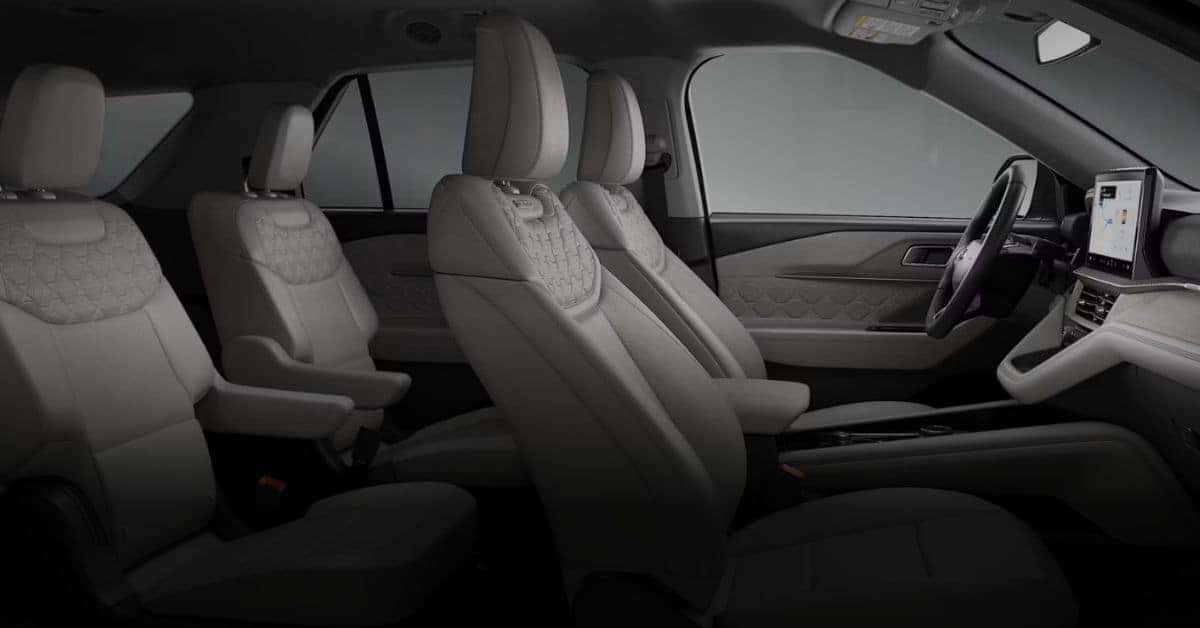 The spacious and modern interior of a Ford Explorer, showcasing the driver's cockpit, steering wheel, dashboard, and front seats in dark leather.