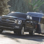 2023 Ford F-150 Hybrid driving on road pulling travel trailer
