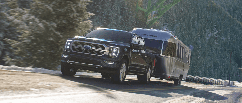 2023 Ford F-150 Hybrid driving on road pulling travel trailer