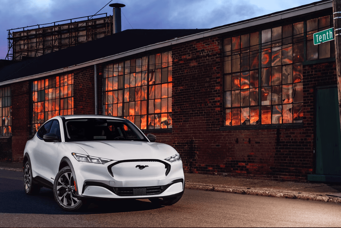 Front view of the 2024 Ford Mustang Mach-E parked outside of a brick building