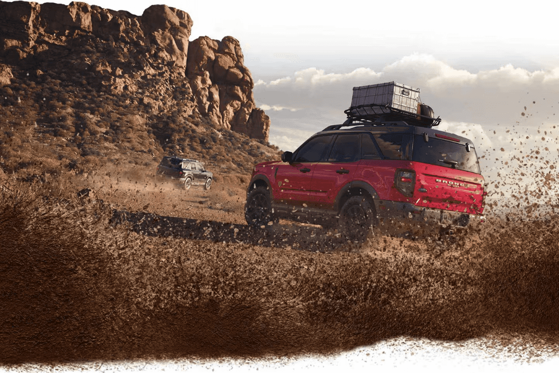 Two 2025 Ford Bronco Sport SUVs on a dirt trail with dirt spraying towards the camera